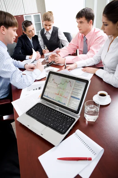Imagem de laptop no local de trabalho com associados falando em segundo plano — Fotografia de Stock