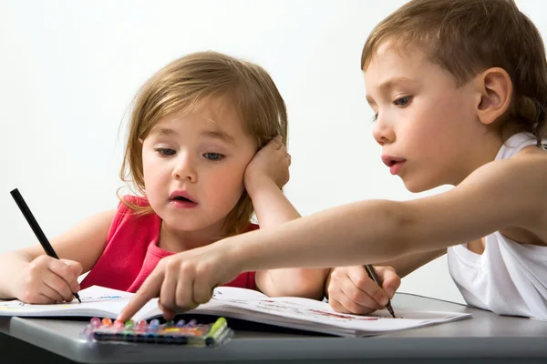 Careful brother shows to his smaller sister the color of felt-tip pen which is better for drawing — Stock Photo, Image