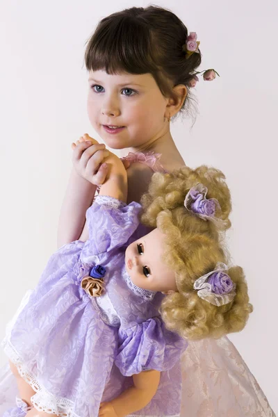 Dolce bruna bambina in abito rosa che tiene la sua bambola — Foto Stock