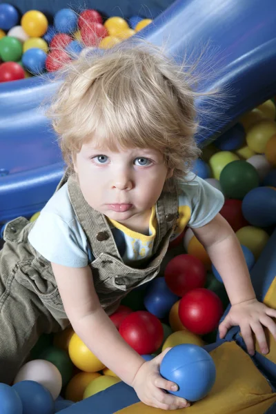 Ragazzo seduto su palline colorate e guardando la fotocamera — Foto Stock