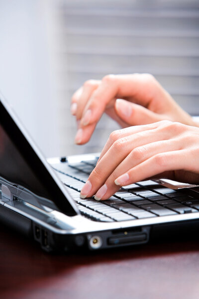 Image of hands typing a letter on the keyboard of laptop