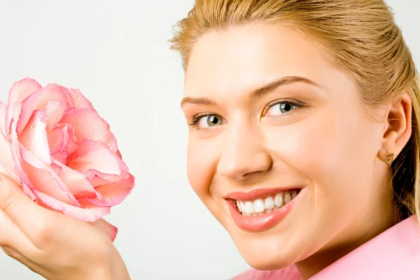 Όμορφη κοπέλα απολαμβάνει μια μυρωδιά από ένα ροζ τριαντάφυλλο — Φωτογραφία Αρχείου