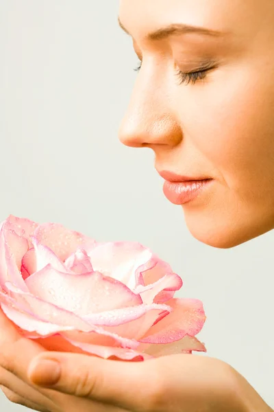 Молода красива жінка насолоджується запахом рожевої троянди — стокове фото