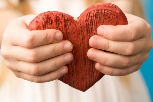 Coração de madeira vermelho nas mãos da criança — Fotografia de Stock
