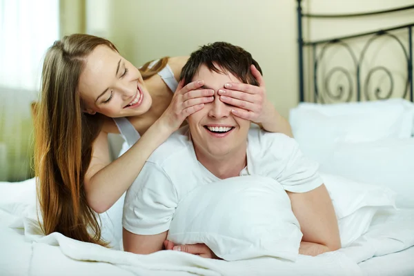 关闭由她的男友眼睛的快乐女孩双手在床上 — 图库照片