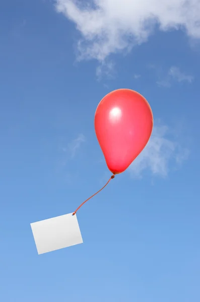Red balloon with greeting card in the sky — Stock Photo, Image