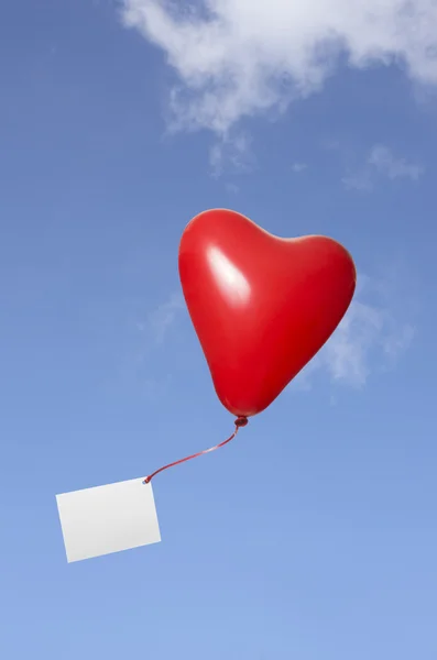 Ballon coeur rouge avec carte de voeux dans le ciel — Photo