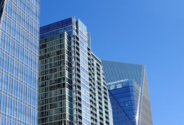 Glass buildings against a blue sky clipart