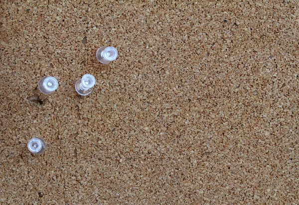 Brown cork board with clear push pins. — Stock Photo, Image