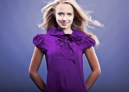 Fille blonde à la mode souriant sur robe violette .