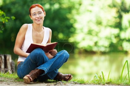 Belle femme assise sur le sol avec un livre 