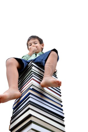 Petit garçon assis sur des livres isolés en blanc 