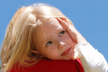 La petite fille sur une épaule à la mère contre le ciel 