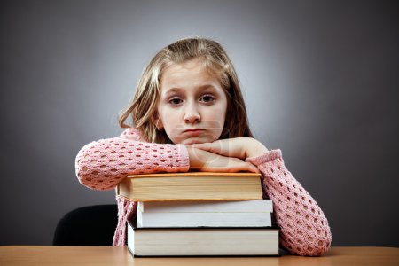 Malheureux écolière avec une pile de livres 