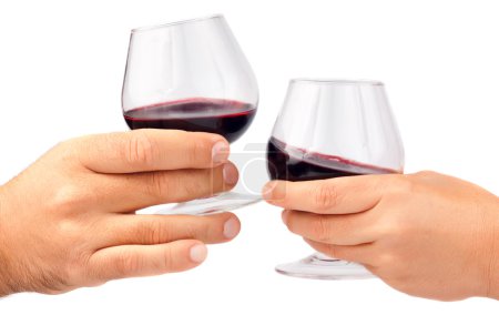 Deux mains tenant des verres à vin rouge 