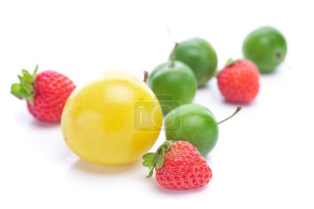 prunes vertes et jaunes et fraises isolées sur blanc 