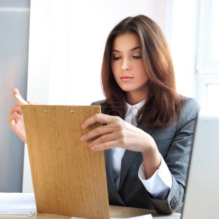 Portrait d'une jeune femme d'affaires dans un bureau avec documents 
