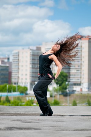 Belle fille dansant style moderne sur le paysage de la ville 