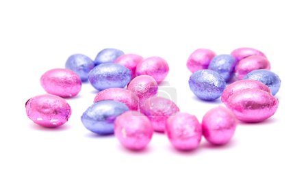 Œufs de Pâques au chocolat en papier rose et lilas, isolés sur du blanc 