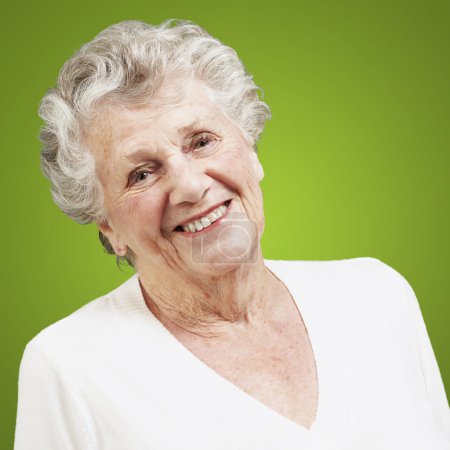 jolie femme âgée souriant sur un fond vert 