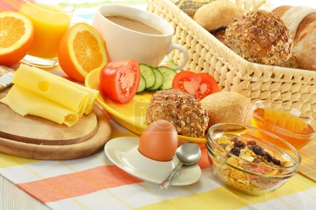 Petit déjeuner comprenant petits pains, oeufs, fromage, café et jus d'orange 