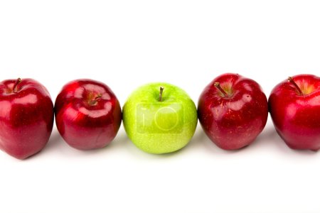 Pomme verte parmi les pommes rouges isolées sur un blanc 
