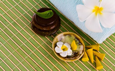 Frangipani fleurs et feuilles avec des pierres zen sur un tapis de bambou 