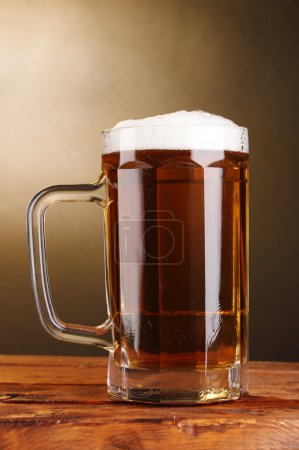tasse de bière sur table en bois sur fond brun 