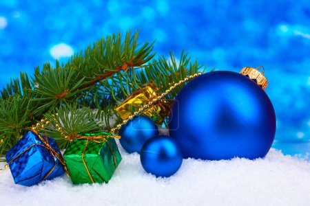 Boule de Noël et jouet avec arbre vert dans la neige sur bleu 