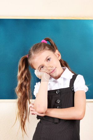 belle petite fille debout près du tableau noir dans la salle de classe 