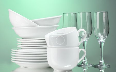 Assiettes, tasses et verres propres sur fond vert 