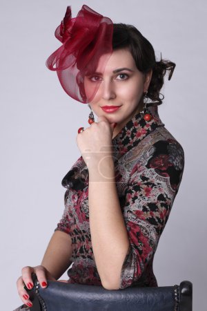 Belle femme avec des boucles d'oreilles en corail et chapeau rouge 