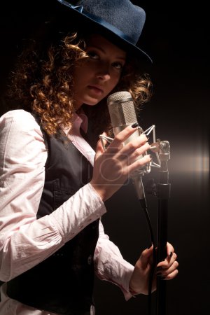 Belle chanteuse en chapeau avec microphone 