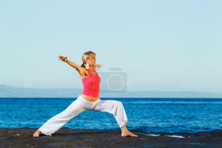 Belle femme de yoga pratiquant le yoga par l'océan 