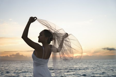 Mariée tenant voile sur la plage .