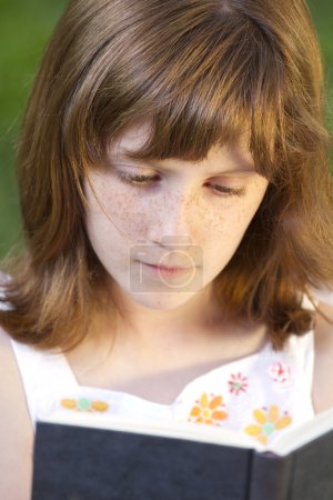 Jeune belle fille lisant un livre en plein air 