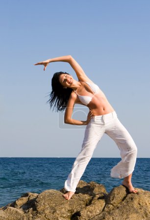 Jeune belle femme faisant des exercices de remise en forme dans la mer 