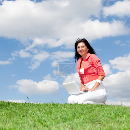 Femme mignonne avec ordinateur portable blanc dans le parc 